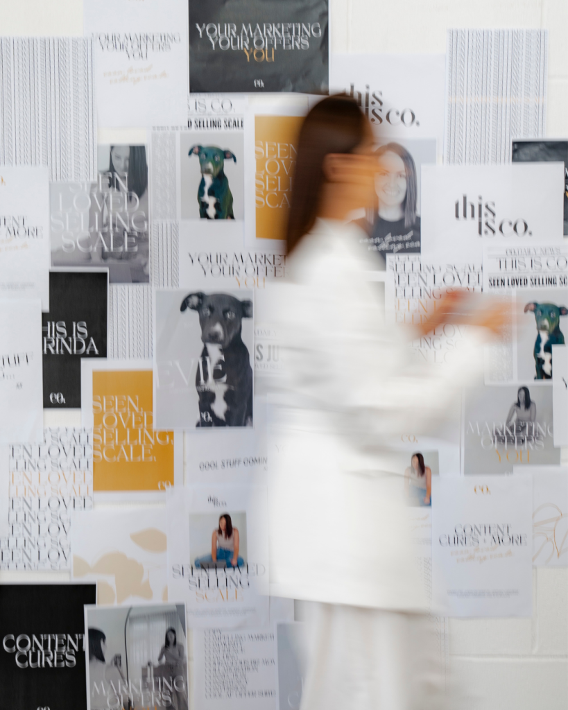 Carinda Gosling walking past a wall of This is Co. and Seen Loved Selling Scale brand prints